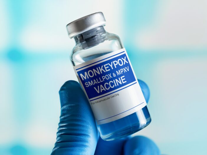 A hand holding a vial of Monkeypox Vaccine